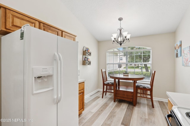1260 Winding Brook Ct, Middleburg, FL 32068 - kitchen with white fridge with ice dispenser, a chandelier, range, light wood-type flooring, and pendant lighting