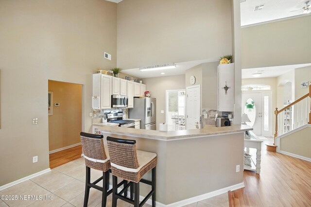 1077 Waterfall Dr, Jacksonville, FL 32225 - kitchen with stainless steel appliances, a high ceiling, tasteful backsplash, a peninsula, and light countertops