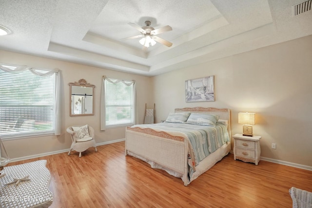 1077 Waterfall Dr, Jacksonville, FL 32225 - bedroom featuring a tray ceiling, multiple windows, light wood-type flooring, baseboards, and a textured ceiling