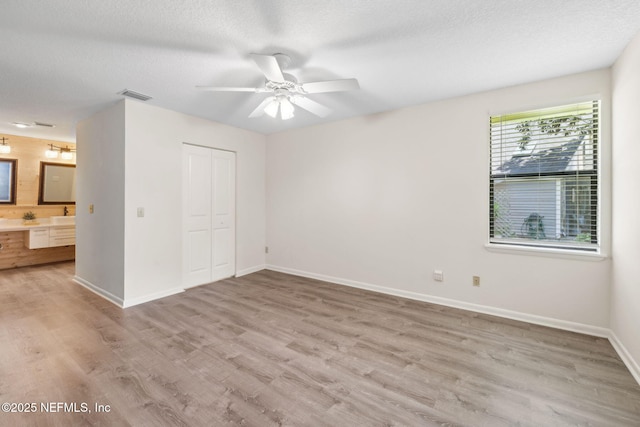 4580 Carolyn Cove Ln N, Jacksonville, FL 32258 - unfurnished bedroom with light wood-style floors, baseboards, a closet, connected bathroom, and a textured ceiling