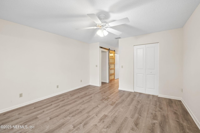4580 Carolyn Cove Ln N, Jacksonville, FL 32258 - unfurnished bedroom with light wood-style floors, baseboards, a closet, a barn door, and ceiling fan