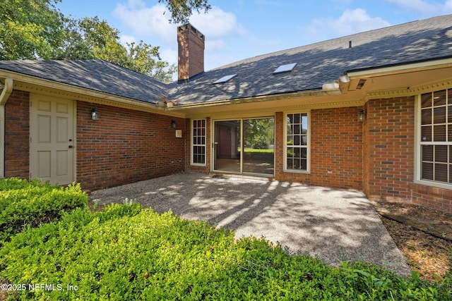 8127 Middle Fork Ln, Jacksonville, FL 32256 - back of house featuring a chimney, brick siding, a patio, and a shingled roof