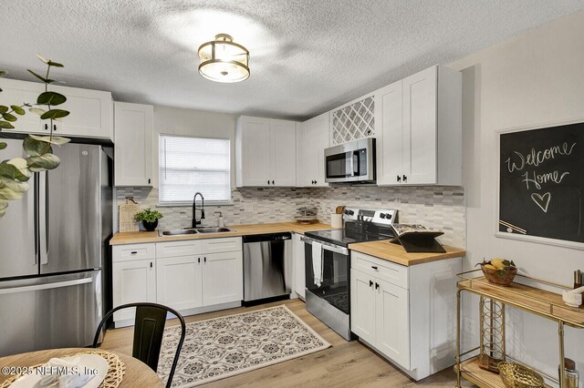 521 Talbot Ave, Jacksonville, FL 32205 - kitchen with appliances with stainless steel finishes, a sink, butcher block counters, decorative backsplash, and light wood finished floors