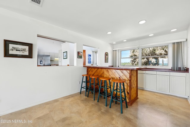 2605 S Ponte Vedra Blvd, Ponte Vedra Beach, FL 32082 - kitchen featuring stainless steel fridge, a breakfast bar, light flooring, recessed lighting, and white cabinets