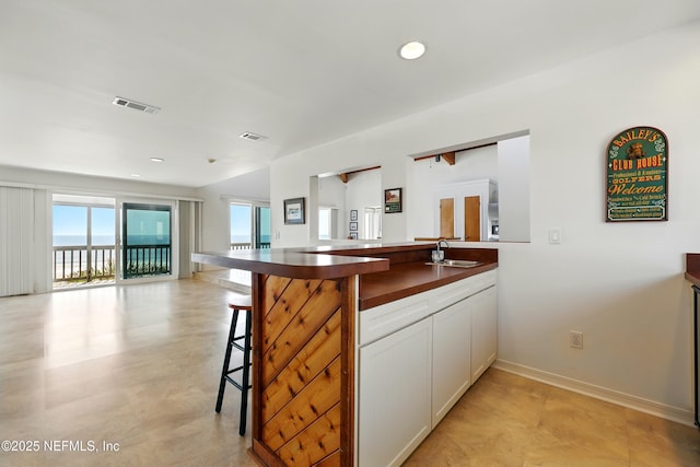 2605 S Ponte Vedra Blvd, Ponte Vedra Beach, FL 32082 - kitchen featuring a sink, open floor plan, dark countertops, a kitchen breakfast bar, and white cabinetry