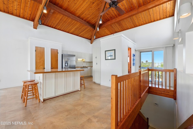 2605 S Ponte Vedra Blvd, Ponte Vedra Beach, FL 32082 - kitchen featuring stainless steel refrigerator with ice dispenser, wood ceiling with exposed beams, a kitchen bar, white cabinetry, and a ceiling fan