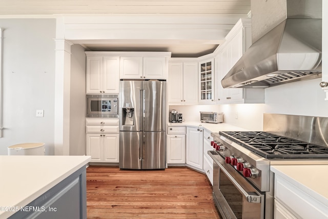 102 Palm Pl, Neptune Beach, FL 32266 - kitchen with stainless steel appliances, wall chimney range hood, white cabinetry, light countertops, and light wood finished floors