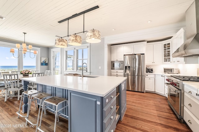 102 Palm Pl, Neptune Beach, FL 32266 - kitchen with appliances with stainless steel finishes, a sink, wall chimney range hood, white cabinets, and a breakfast bar