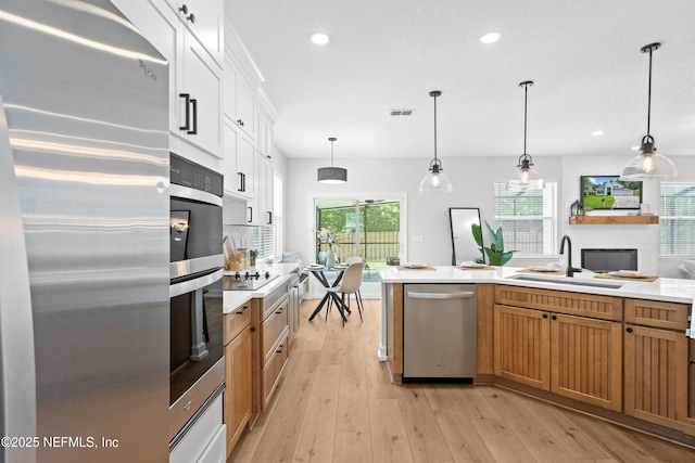 1008 Durbin Parke Dr, Saint Johns, FL 32259 - kitchen featuring appliances with stainless steel finishes, a sink, light countertops, light wood-type flooring, and decorative light fixtures