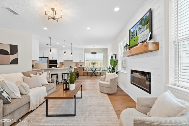 1008 Durbin Parke Dr, Saint Johns, FL 32259 - living area featuring light wood finished floors, recessed lighting, a glass covered fireplace, a chandelier, and baseboards
