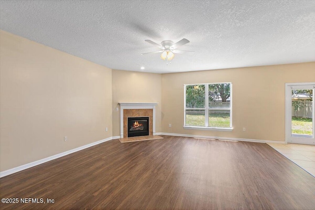 1147 Hyacinth St, Saint Augustine, FL 32092 - unfurnished living room featuring wood finished floors, a ceiling fan, a tile fireplace, baseboards, and a textured ceiling
