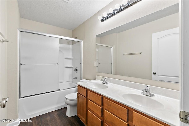 4952 Cypress Links Blvd, Elkton, FL 32033 - full bathroom featuring double vanity, wood finished floors, toilet, bath / shower combo with glass door, and a textured ceiling