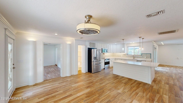 26 Sailfish Dr, Ponte Vedra Beach, FL 32082 - kitchen featuring stainless steel appliances, light countertops, white cabinets, light wood-type flooring, and ornamental molding