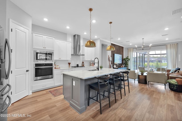 95 Farmers Branch Ave, Ponte Vedra, FL 32081 - kitchen featuring stainless steel appliances, wall chimney range hood, a sink, a breakfast bar area, and light wood-type flooring