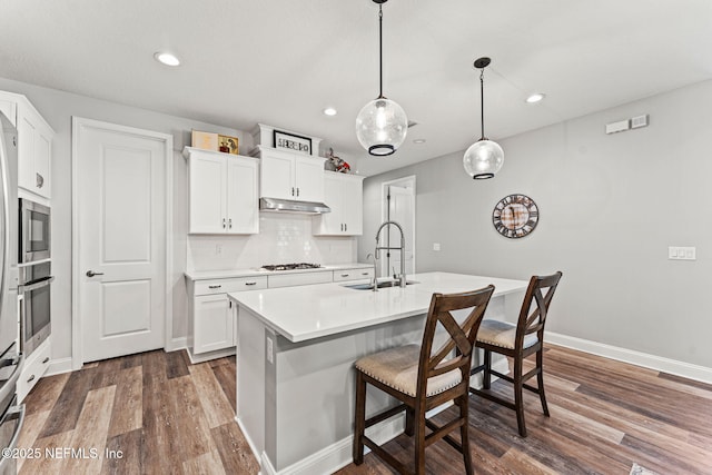 68 Cabana Dr, Ponte Vedra, FL 32081 - kitchen with a sink, under cabinet range hood, dark wood-type flooring, a breakfast bar area, and light countertops