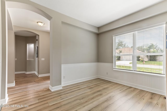 3820 Danforth Dr W, Jacksonville, FL 32224 - unfurnished room featuring light wood-style flooring, arched walkways, wainscoting, and baseboards