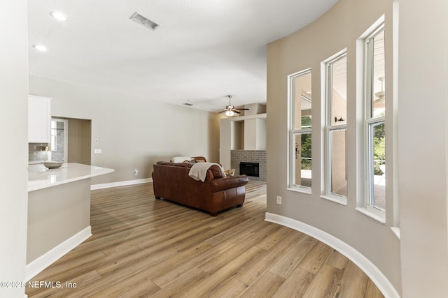 3820 Danforth Dr W, Jacksonville, FL 32224 - living room with a brick fireplace, light wood-style floors, ceiling fan, and baseboards