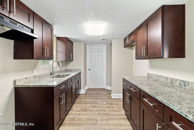2718 Parkrus Ln, Jacksonville, FL 32208 - kitchen featuring a sink, under cabinet range hood, light wood-type flooring, light stone countertops, and a textured ceiling