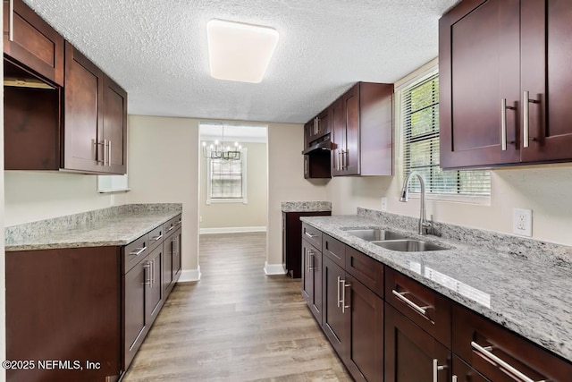 2718 Parkrus Ln, Jacksonville, FL 32208 - kitchen with a sink, a textured ceiling, baseboards, a chandelier, and light wood-style flooring