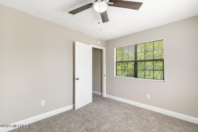 2718 Parkrus Ln, Jacksonville, FL 32208 - unfurnished bedroom with light colored carpet, baseboards, a textured ceiling, and a ceiling fan