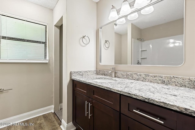 2718 Parkrus Ln, Jacksonville, FL 32208 - bathroom with wood finished floors, baseboards, a textured ceiling, vanity, and a shower
