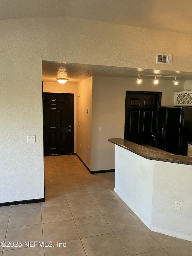 425 Timberwalk Ct Unit 1135, Ponte Vedra Beach, FL 32082 - kitchen featuring black fridge, rail lighting, dark countertops, light tile patterned floors, and a textured wall