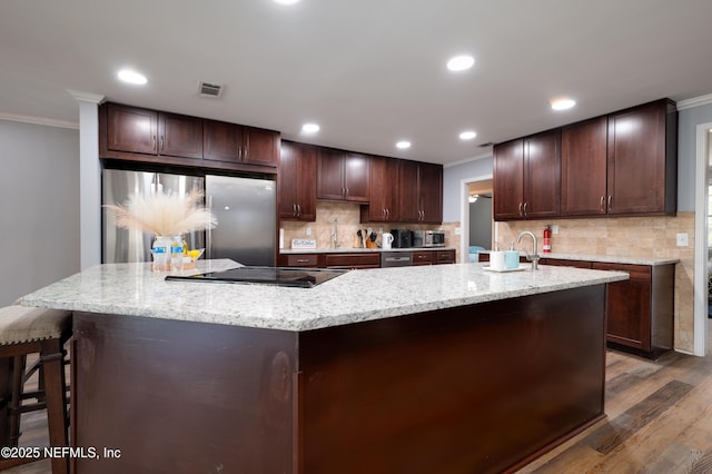 5253 Royce Ave, Jacksonville, FL 32205 - kitchen with ornamental molding, a large island with sink, stainless steel refrigerator, wood finished floors, and decorative backsplash
