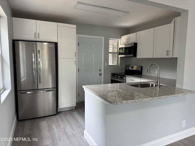 3114 Breve Dr, Jacksonville, FL 32209 - kitchen with appliances with stainless steel finishes, a sink, light stone counters, light wood finished floors, and a peninsula