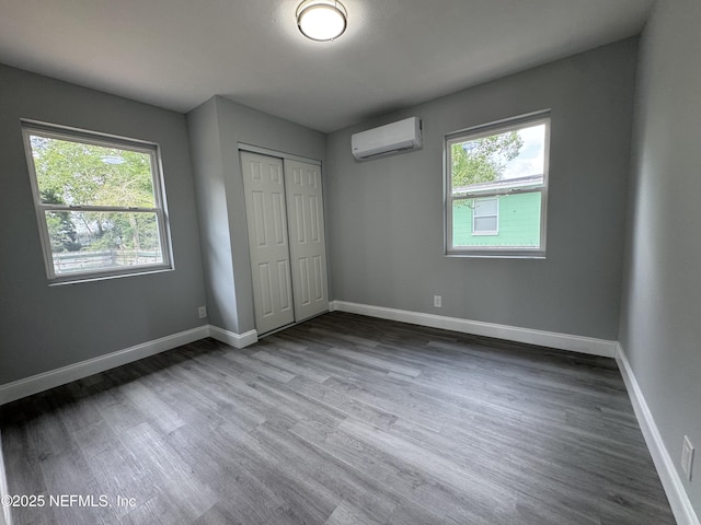 3114 Breve Dr, Jacksonville, FL 32209 - unfurnished bedroom with wood finished floors, a closet, a wall unit AC, and baseboards
