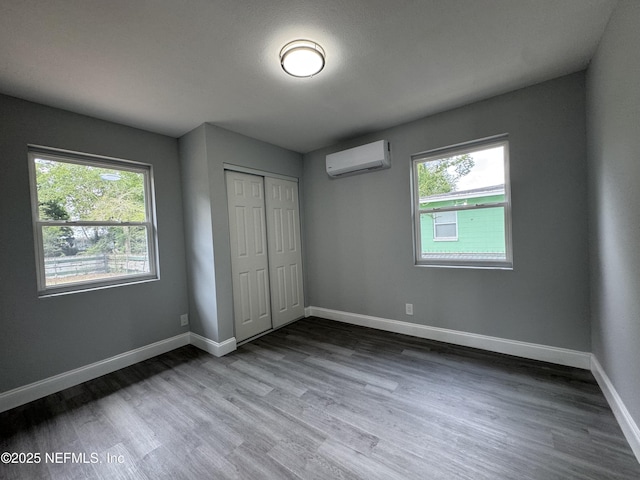 3114 Breve Dr, Jacksonville, FL 32209 - unfurnished bedroom featuring a wall mounted air conditioner, multiple windows, wood finished floors, and a closet