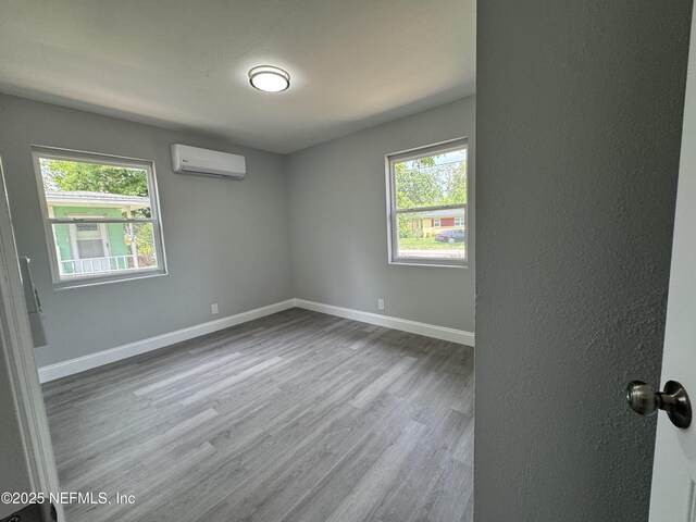 3114 Breve Dr, Jacksonville, FL 32209 - unfurnished room featuring an AC wall unit, healthy amount of natural light, wood finished floors, and baseboards