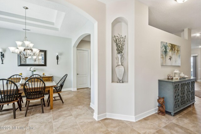 32479 Willow Parke Cir, Fernandina Beach, FL 32034 - dining area with light tile patterned flooring, arched walkways, baseboards, and a chandelier