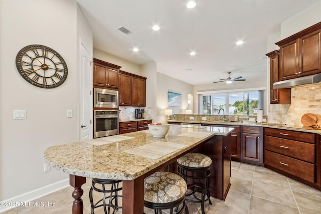 32479 Willow Parke Cir, Fernandina Beach, FL 32034 - kitchen with stainless steel appliances, decorative backsplash, a kitchen breakfast bar, a kitchen island, and a sink