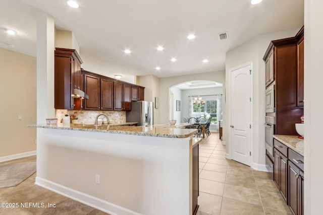 32479 Willow Parke Cir, Fernandina Beach, FL 32034 - kitchen featuring arched walkways, stainless steel appliances, ventilation hood, a peninsula, and tasteful backsplash