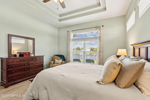32479 Willow Parke Cir, Fernandina Beach, FL 32034 - bedroom with light wood finished floors, a tray ceiling, and a ceiling fan