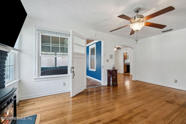 5372 Colonial Ave, Jacksonville, FL 32210 - unfurnished living room with arched walkways, baseboards, light wood-style flooring, ceiling fan, and a textured ceiling