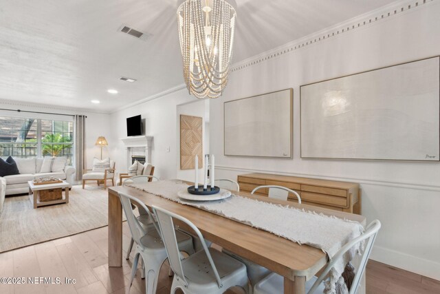 1908 Springbrook Rd, Fernandina Beach, FL 32034 - dining area featuring a chandelier, wood finished floors, baseboards, crown molding, and a fireplace