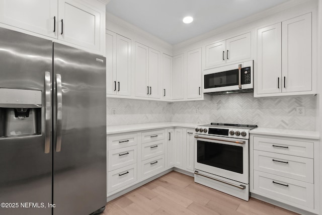 1908 Springbrook Rd, Fernandina Beach, FL 32034 - kitchen featuring white appliances, light countertops, white cabinets, light wood-style flooring, and decorative backsplash