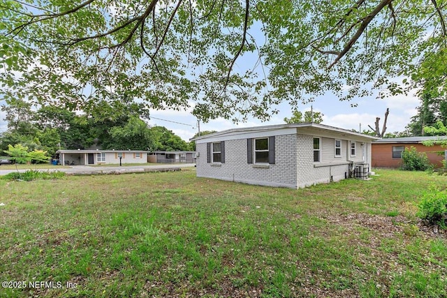 222 Acme St, Jacksonville, FL 32211 - rear view of house featuring brick siding, a lawn, and central AC unit