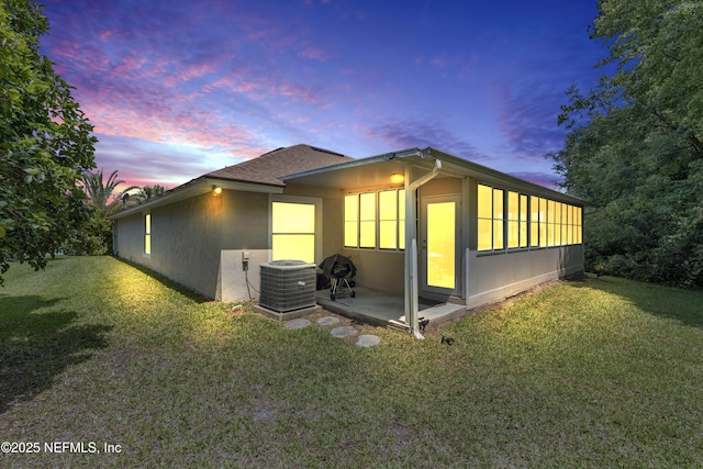 2097 Frogmore Dr, Middleburg, FL 32068 - property exterior at dusk featuring central air condition unit, a yard, and stucco siding