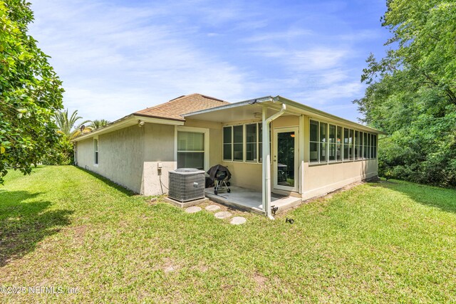 2097 Frogmore Dr, Middleburg, FL 32068 - back of property with central air condition unit, stucco siding, a sunroom, a yard, and roof with shingles