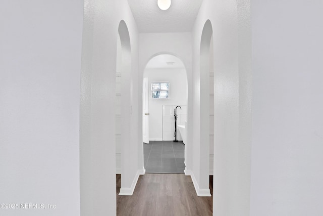 3409 Steelgate Ct, Middleburg, FL 32068 - hallway featuring arched walkways, wood finished floors, baseboards, and a textured ceiling