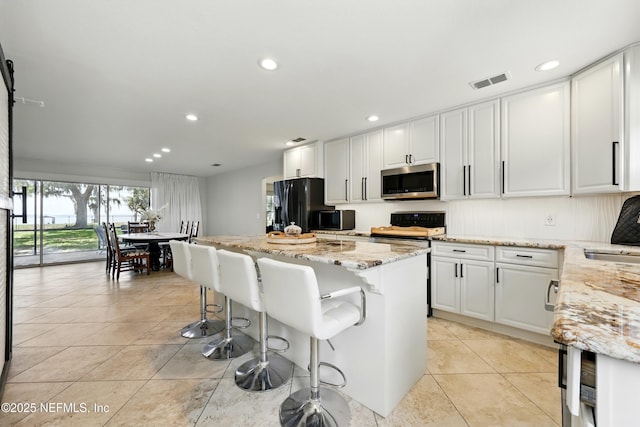 13900 County Road 13 N, Saint Augustine, FL 32092 - kitchen with stainless steel microwave, stove, light stone counters, a kitchen island, and recessed lighting