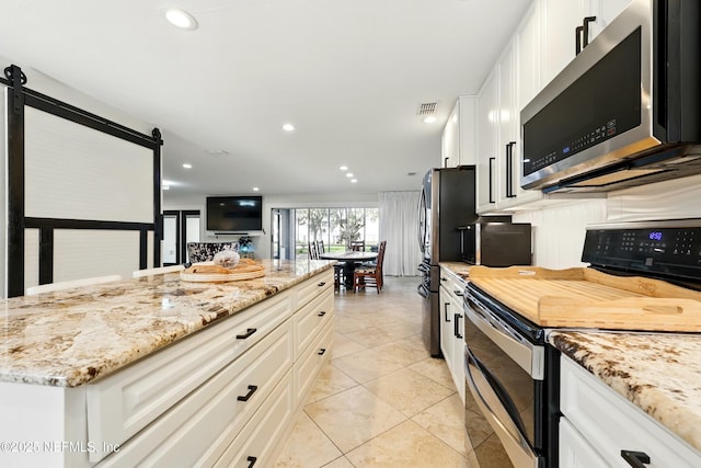 13900 County Road 13 N, Saint Augustine, FL 32092 - kitchen with appliances with stainless steel finishes, light stone counters, light tile patterned flooring, white cabinetry, and recessed lighting