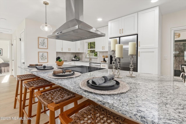 1129 Sebago Ave N, Jacksonville, FL 32233 - kitchen featuring island range hood, a breakfast bar, a sink, white cabinetry, and light stone counters