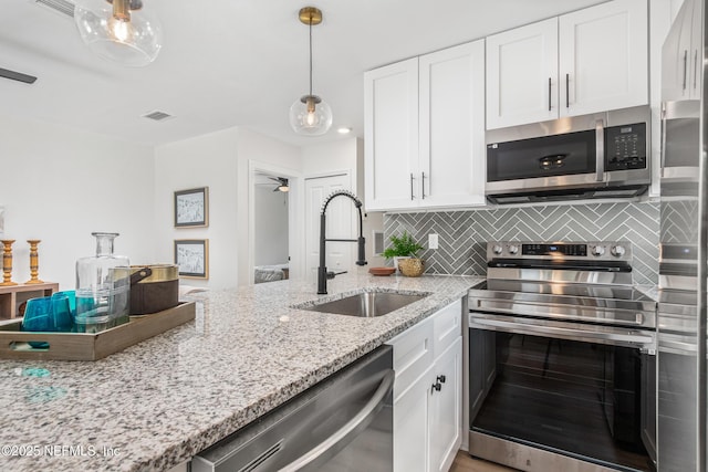 3832 Bunnell Dr, Jacksonville, FL 32246 - kitchen with appliances with stainless steel finishes, a sink, white cabinetry, and light stone countertops