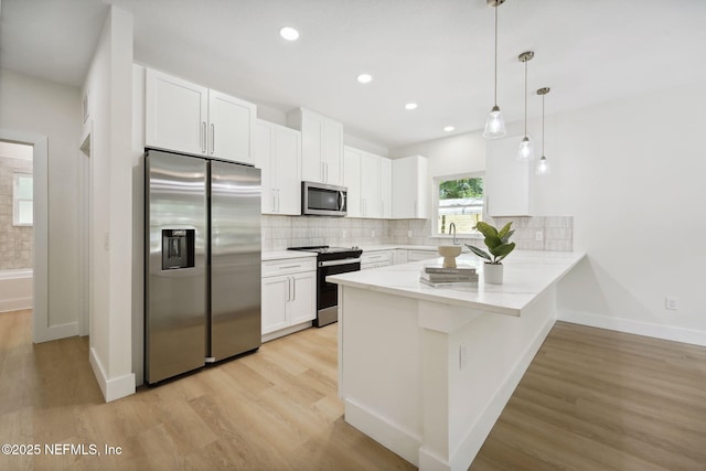 771 W 4th St, Saint Augustine, FL 32084 - kitchen with stainless steel appliances, a peninsula, white cabinets, light wood-style floors, and tasteful backsplash