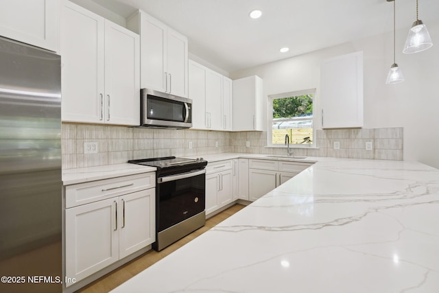 771 W 4th St, Saint Augustine, FL 32084 - kitchen with stainless steel appliances, a sink, white cabinetry, light wood-style flooring, and decorative light fixtures