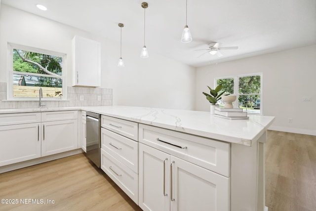 771 W 4th St, Saint Augustine, FL 32084 - kitchen with stainless steel dishwasher, a peninsula, ceiling fan, decorative backsplash, and white cabinetry