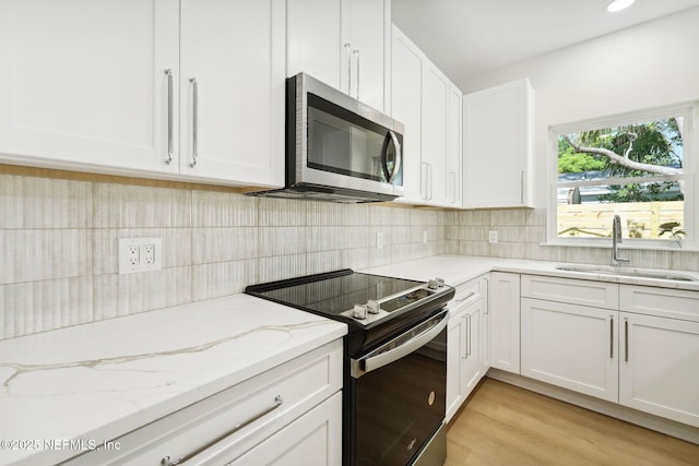 771 W 4th St, Saint Augustine, FL 32084 - kitchen featuring stainless steel microwave, electric stove, a sink, and white cabinets